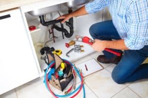 Plumbing about to tighten a pipe under a sink