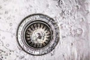 Closeup of a kitchen sink drain with water in the sink