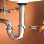 Closeup of a wrench tightening a pipe under a sink