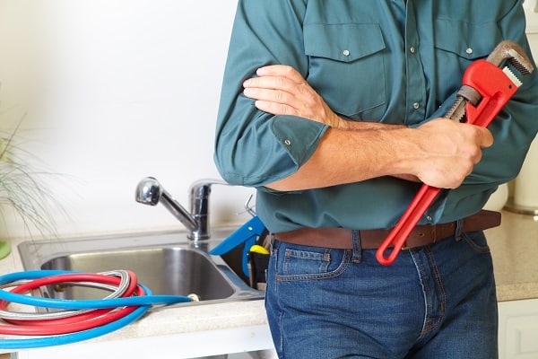 Plumber in a kitchen fixing a stopped up sink drain